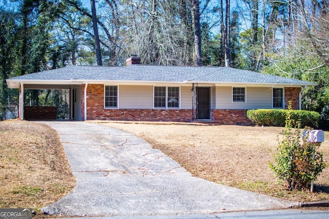 ranch-style house with driveway, a chimney, an attached carport, roof with shingles, and brick siding