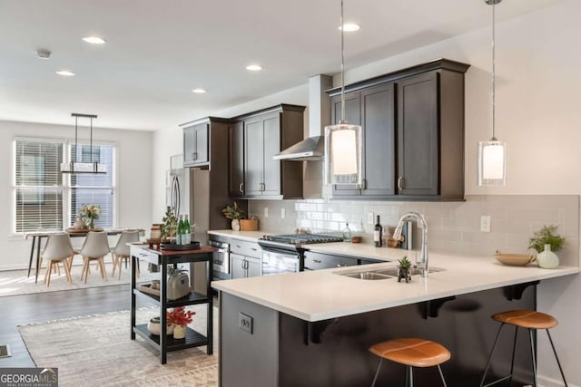 kitchen with stainless steel appliances, light countertops, hanging light fixtures, backsplash, and a sink