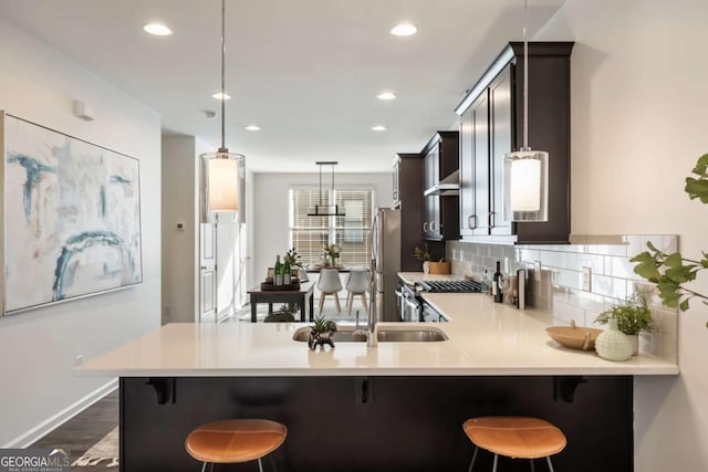 kitchen with a peninsula, dark wood-style floors, light countertops, decorative backsplash, and stainless steel appliances