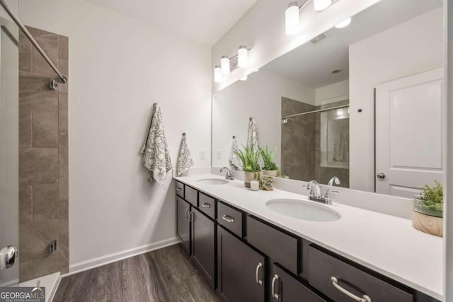 full bathroom featuring a sink, baseboards, tiled shower, and wood finished floors