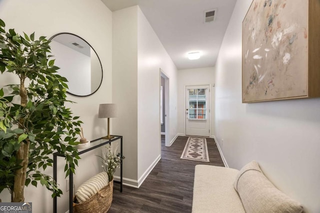 corridor featuring wood finished floors, baseboards, and visible vents