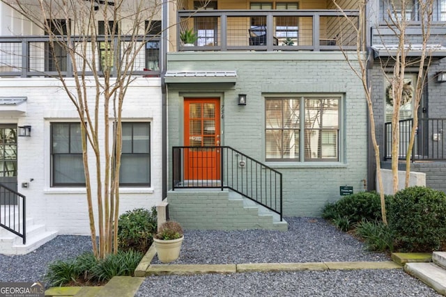 doorway to property featuring metal roof and brick siding