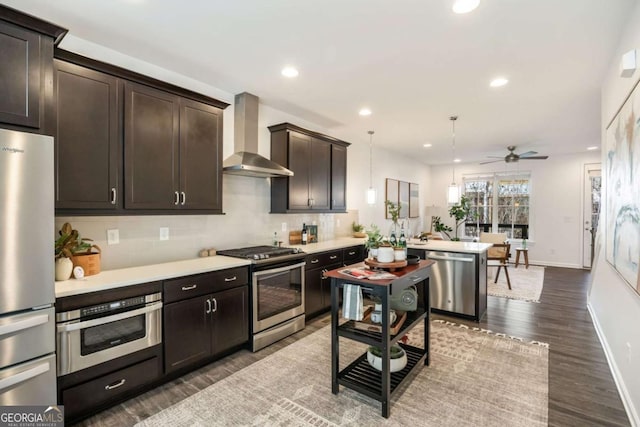 kitchen featuring stainless steel appliances, dark brown cabinetry, wall chimney exhaust hood, and light countertops