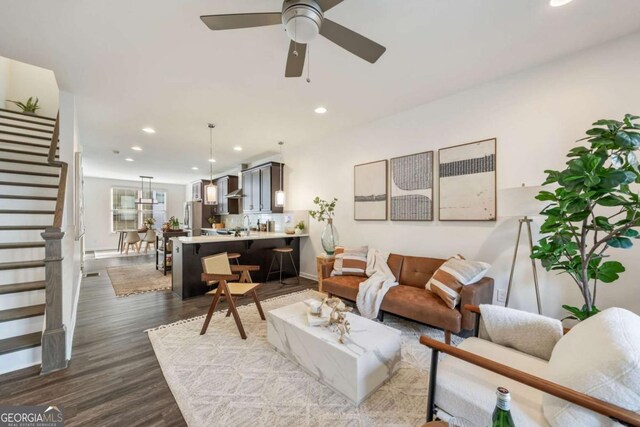 living room featuring a ceiling fan, recessed lighting, dark wood finished floors, and stairway