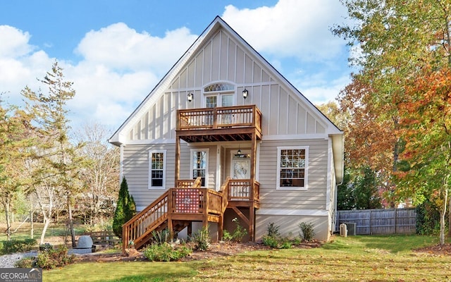 view of front of house featuring central AC unit, a balcony, fence, a front lawn, and board and batten siding