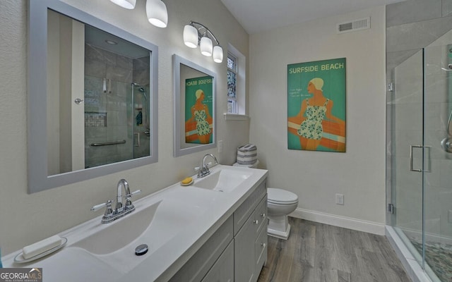 full bathroom featuring visible vents, toilet, a stall shower, a sink, and wood finished floors