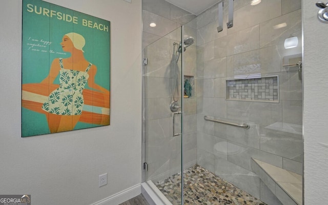 bathroom featuring toilet, a shower stall, and baseboards