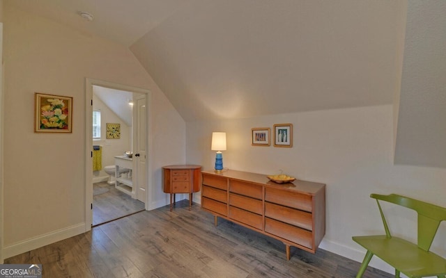 bedroom with lofted ceiling, wood finished floors, connected bathroom, and baseboards