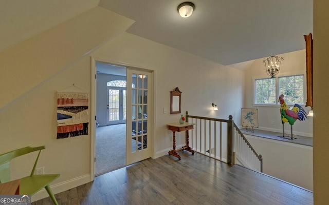 interior space featuring a chandelier, lofted ceiling, baseboards, and wood finished floors