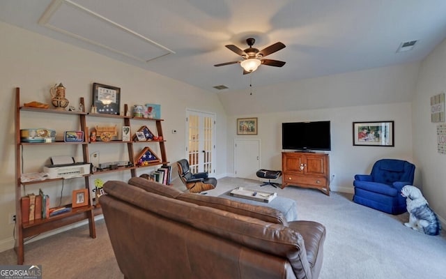 living area featuring attic access, visible vents, vaulted ceiling, and light colored carpet