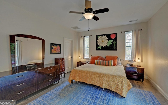 bedroom featuring light wood finished floors, baseboards, visible vents, and a ceiling fan