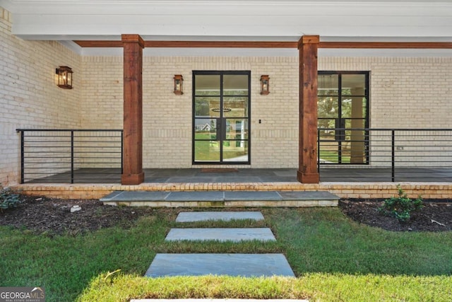 view of exterior entry featuring a porch and brick siding