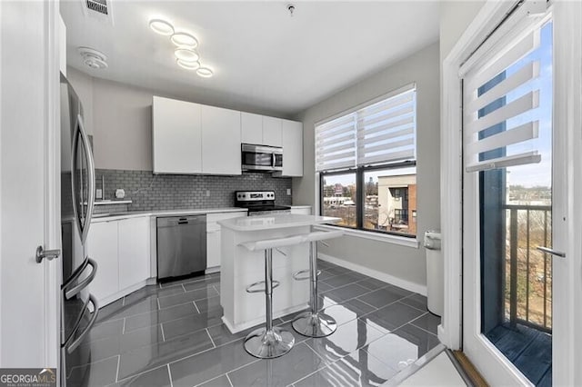 kitchen featuring light countertops, appliances with stainless steel finishes, a kitchen island, and white cabinetry