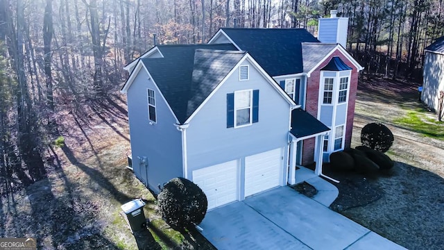 view of front of house featuring an attached garage, driveway, a chimney, and stucco siding