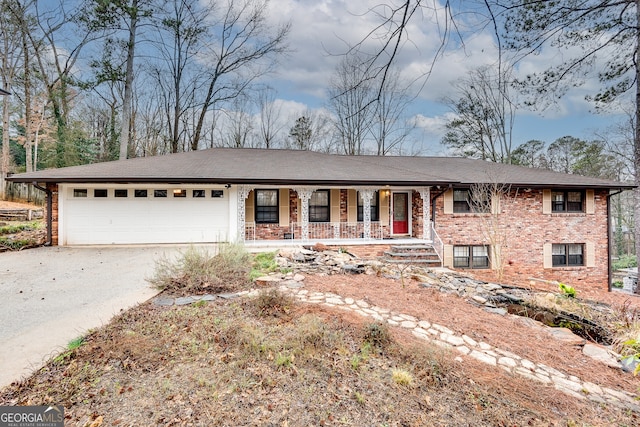 ranch-style house featuring driveway, covered porch, a garage, and brick siding