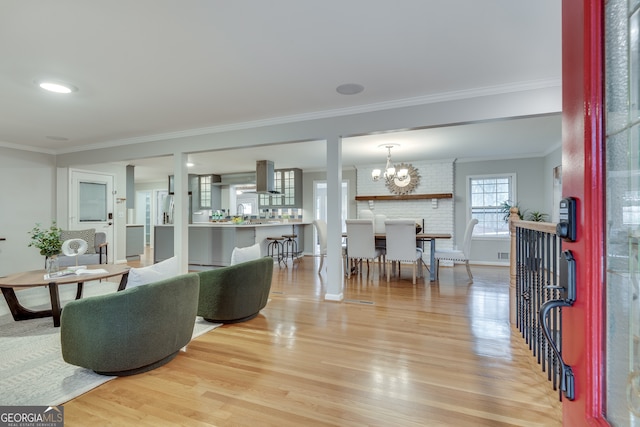 living room featuring light wood-type flooring, baseboards, ornamental molding, and a chandelier