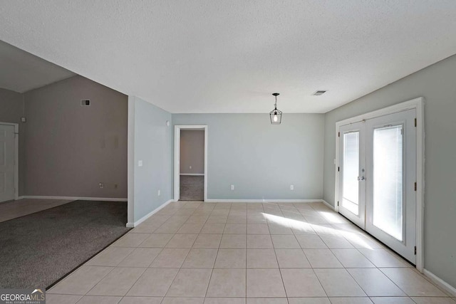 empty room featuring light tile patterned floors, baseboards, visible vents, a textured ceiling, and french doors