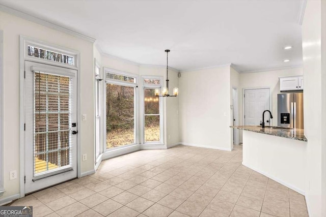 unfurnished dining area with light tile patterned floors, a notable chandelier, a sink, baseboards, and crown molding