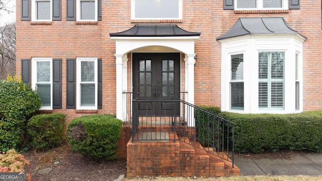 doorway to property featuring a standing seam roof, brick siding, and metal roof