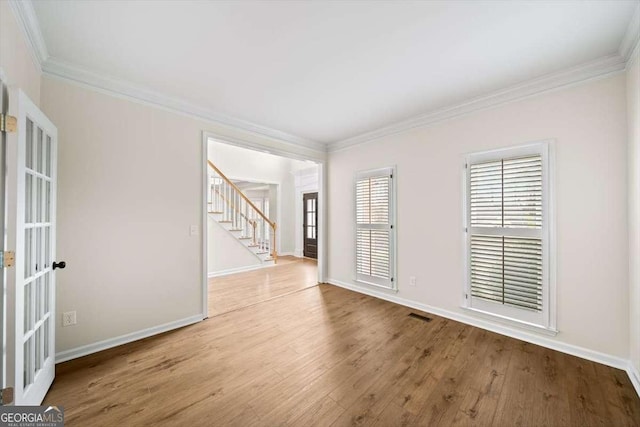 unfurnished room with crown molding, baseboards, and light wood-style floors