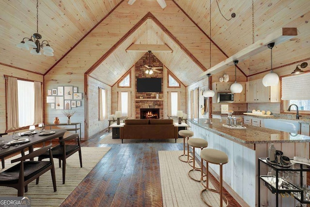 kitchen with light stone counters, pendant lighting, stainless steel microwave, and wooden ceiling