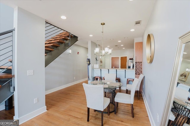 dining room featuring a notable chandelier, baseboards, stairway, light wood-style floors, and visible vents