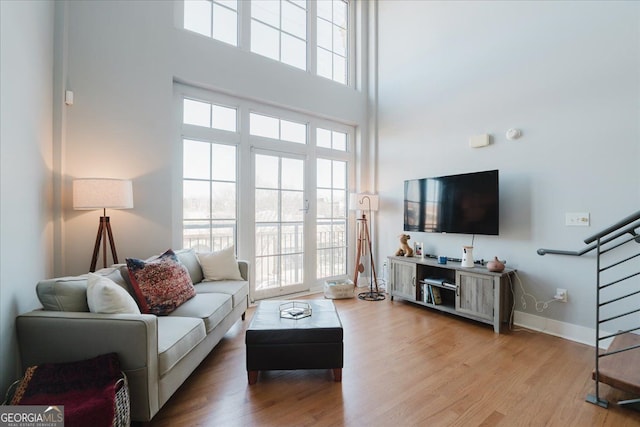 1253 Caroline St NE Unit 223, Atlanta, GA 30307 - living room featuring a towering ceiling, wood finished floors, baseboards, and stairs
