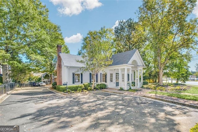 greek revival inspired property featuring a chimney and fence