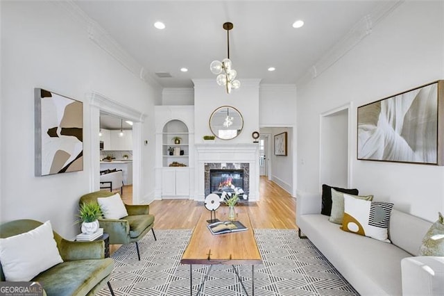 living room featuring ornamental molding, recessed lighting, light wood-style floors, and a premium fireplace