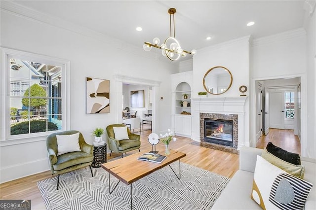 living room with ornamental molding, a chandelier, light wood-style flooring, and baseboards