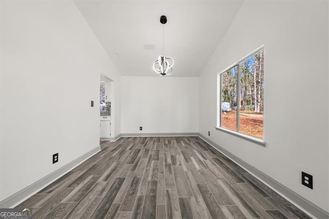 unfurnished dining area with high vaulted ceiling, a notable chandelier, baseboards, and dark wood-style flooring