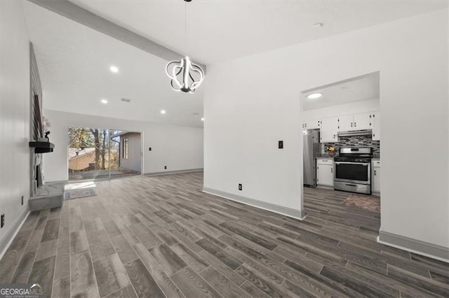 unfurnished living room with dark wood-style flooring, recessed lighting, lofted ceiling, an inviting chandelier, and baseboards