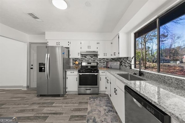 kitchen featuring visible vents, appliances with stainless steel finishes, under cabinet range hood, white cabinetry, and a sink