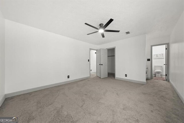 unfurnished bedroom featuring a textured ceiling, ceiling fan, light colored carpet, visible vents, and baseboards