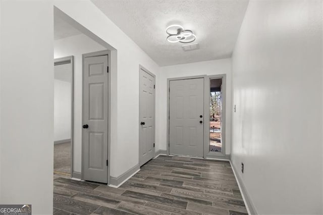 entryway featuring visible vents, a textured ceiling, baseboards, and dark wood-style flooring