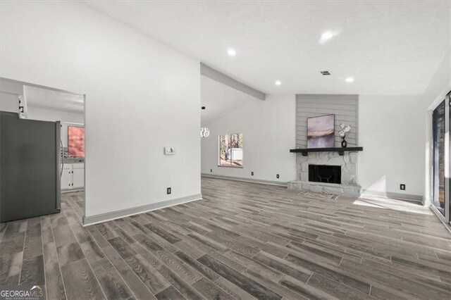 unfurnished living room featuring a large fireplace, baseboards, visible vents, dark wood-style floors, and beamed ceiling