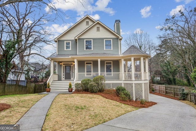 view of front of home with a chimney, fence, a front lawn, and a porch