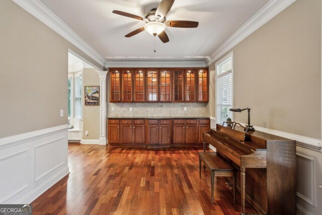 bar with dark wood-style floors, a wainscoted wall, crown molding, a decorative wall, and decorative backsplash