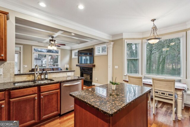 kitchen with dishwasher, dark stone countertops, a center island, hanging light fixtures, and a sink