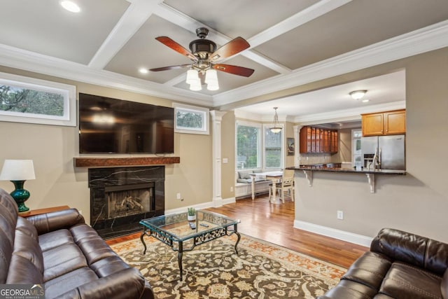 living room featuring a premium fireplace, coffered ceiling, wood finished floors, and baseboards