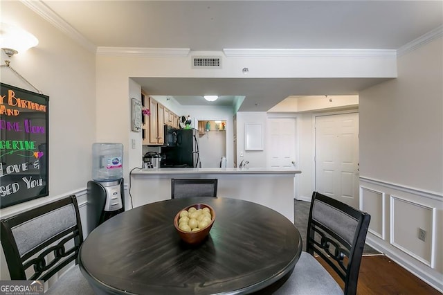 dining space with dark wood-style flooring, a wainscoted wall, visible vents, a decorative wall, and ornamental molding