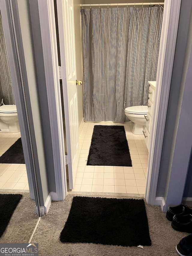 bathroom with toilet, vanity, and tile patterned floors