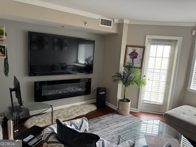 living room with baseboards, wood finished floors, visible vents, and crown molding