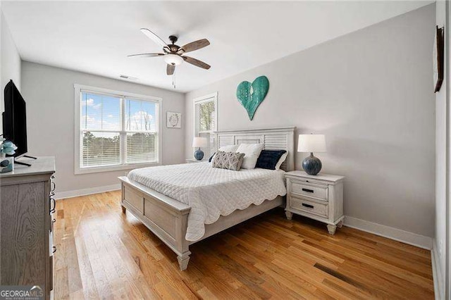 bedroom with light wood-type flooring, baseboards, and a ceiling fan