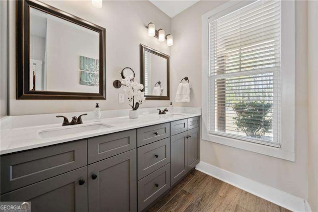 full bathroom featuring double vanity, a sink, baseboards, and wood finished floors