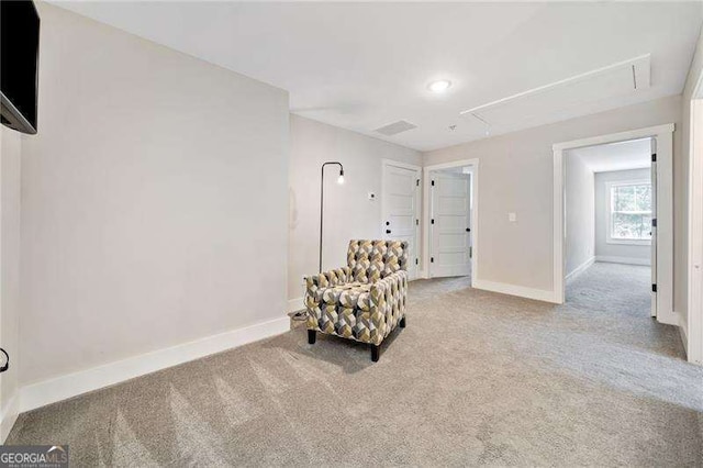 living area featuring carpet floors, attic access, and baseboards