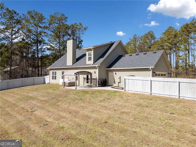 back of property featuring a fenced backyard, a chimney, an attached garage, a yard, and a patio area