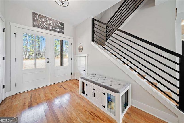 entryway featuring french doors, stairway, and light wood finished floors