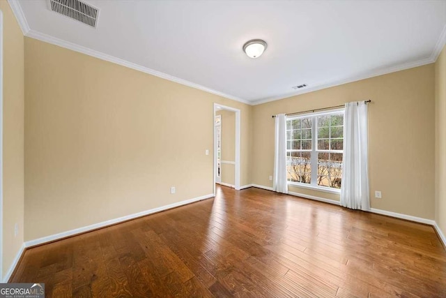 empty room with hardwood / wood-style flooring, baseboards, and visible vents