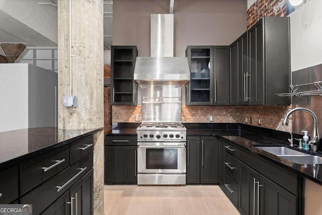 kitchen with high end stainless steel range oven, glass insert cabinets, dark stone counters, and wall chimney range hood